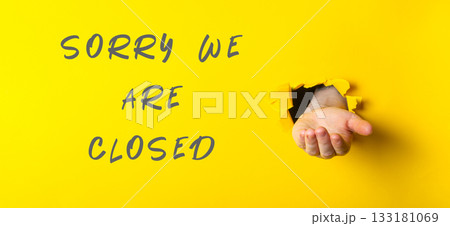Sorry we are closed sign with a hand holding a hole in it 133181069