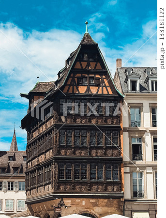 Historic timber-framed building stands proudly among modern architecture, showcasing intricate details and vibrant colors against a clear blue sky Historic timber-framed building stands proudly among modern architecture, showcasing intricate details and vibrant colors against a clear blue sky 133181122