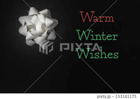 White gift bow on dark background with warm winter wishes for festive holiday celebrations 133181175