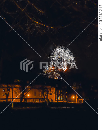 Colorful fireworks display illuminating night sky over urban landscape with glowing streetlights Colorful fireworks display illuminating night sky over urban landscape with glowing streetlights 133181218
