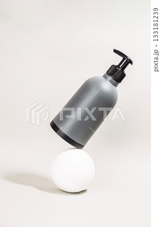 Bottle of liquid soap is on top of a white ball 133181239