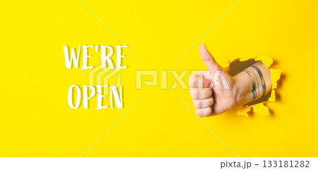 hand on yellow background with thumb up with inscription Were open hand on yellow background with thumb up with inscription Were open 133181282