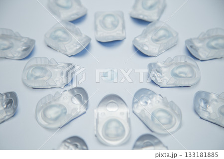 A creative layout in the form of a three-dimensional flower lies in one-day contact lenses in disposable protective packaging, in the center there is a transparent contact lens on a white background A creative layout in the form of a three-dimensional flower lies in one-day contact lenses in disposable protective packaging, in the center there is a transparent contact lens on a white background 133181885