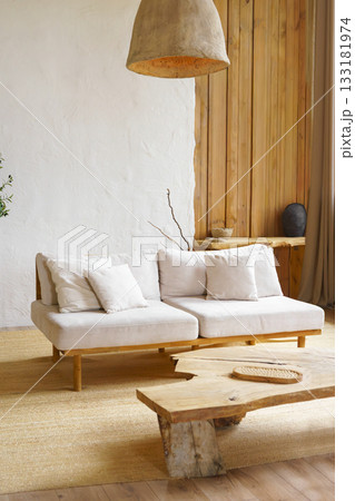 Modern minimalist interior of living room with beige sofa, rustic wooden table in natural light Modern minimalist interior of living room with beige sofa, rustic wooden table in natural light 133181974