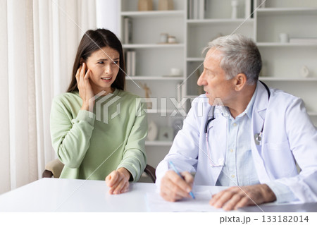 Pregnant woman feeling pain while consulting with senior male doctor in clinic Pregnant woman feeling pain while consulting with senior male doctor in clinic 133182014