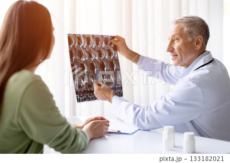 Senior male doctor showing Xray to female patient during consultation in clinic 133182021