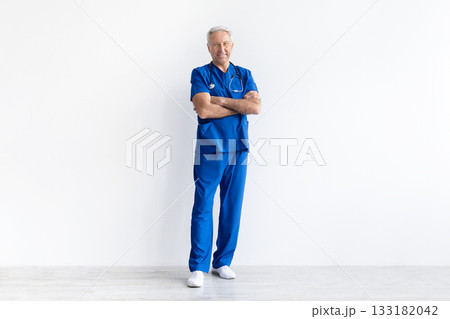 Senior male doctor in uniform standing with arms crossed on white background 133182042