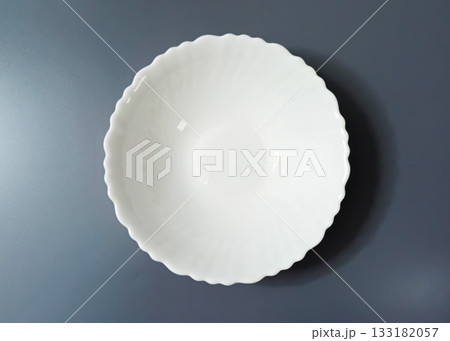 Empty White Soup Plate with Wavy Edge on gray Background Empty White Soup Plate with Wavy Edge on gray Background 133182057