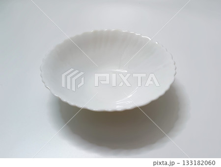 Empty White Deep Plate with Wavy Edge on Light Background 133182060