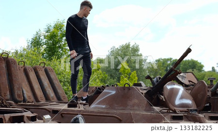Young man looking at destroyed military equipment of the russian army. Exhibition of rusty and burned-out armored vehicles on ukrainian territory. War between Ukraine and russia. Slow motion 133182225