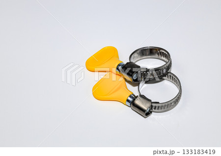 Steel Worm Gear Hose Clamp with yellow thumb screw key, Screw clamp or Hose clamps or Steel clamps isolated on white background. Steel Worm Gear Hose Clamp with yellow thumb screw key, Screw clamp or Hose clamps or Steel clamps isolated on white background. 133183419