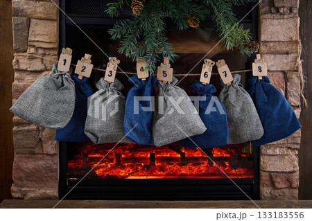 Cozy Advent Calendar. A cozy fireplace scene with numbered advent bags Cozy Advent Calendar. A cozy fireplace scene with numbered advent bags 133183556