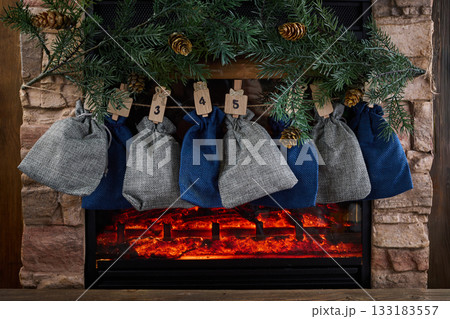 Cozy Advent Calendar. A cozy fireplace scene with numbered advent bags 133183557