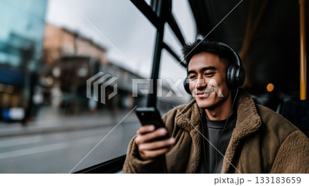 Smartphones as means of communicating with world and creating personal space urban environment, native American man with smartphone and headphones smiles while listening to music on his way to work 133183659
