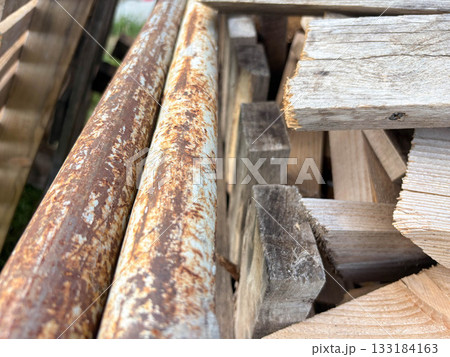 Old rusty iron pipes and wooden planks in a pile. Construction waste. Old rusty iron pipes and wooden planks in a pile. Construction waste. 133184163
