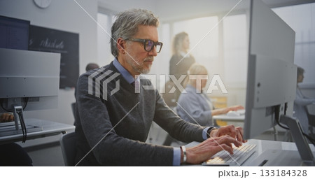 Stylish Senior Man With Glasses Works Attentively at Desktop Computer During Programming Course 133184328