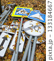 Autumn leaves cover piles of road signs and posts. 133184667