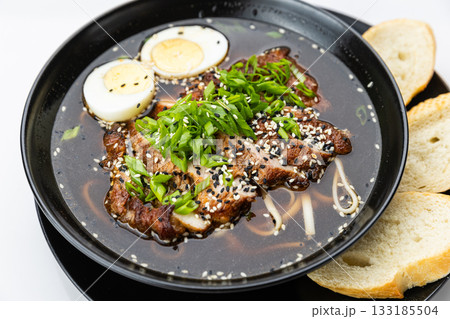 Black bowl of soy ramen with sliced pork, egg, scallions and sesame, isolated on white Black bowl of soy ramen with sliced pork, egg, scallions and sesame, isolated on white 133185504