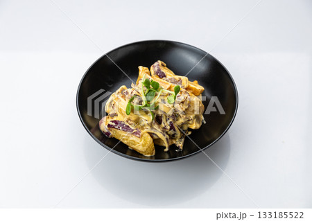 Potato wedges in creamy mushroom sauce with red onion, black bowl, studio top view Potato wedges in creamy mushroom sauce with red onion, black bowl, studio top view 133185522