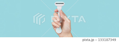 Precision in hand: A razor held against a striking blue backdrop, capturing the essence of grooming finesse 133187349