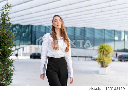 Businesswoman with laptop standing near modern Businesswoman with laptop standing near modern 133188139