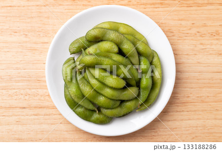 Boiled Edamame beans (Japanese soybeans) on white plate, Table top view Boiled Edamame beans (Japanese soybeans) on white plate, Table top view 133188286