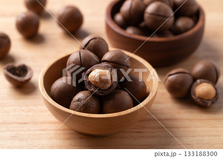 Unpeeled Macadamia nuts in bowl on wooden background 133188300