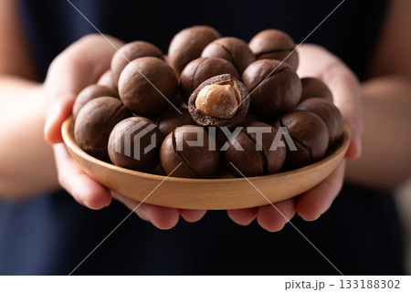 Macadamia nuts in a bowl holding by hand Macadamia nuts in a bowl holding by hand 133188302
