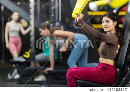 Latina woman doing shoulder press in machine 133188367