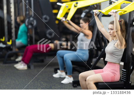 Determined young woman training upper body muscles 133188436
