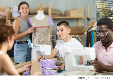 Interested guy working at machine during group sewing course for adults Interested guy working at machine during group sewing course for adults 133188448