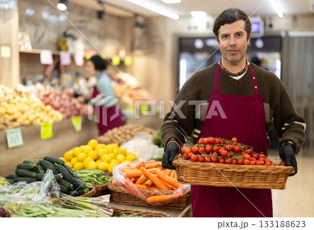 Adult man seller with basket of cherry tomatoes Adult man seller with basket of cherry tomatoes 133188623