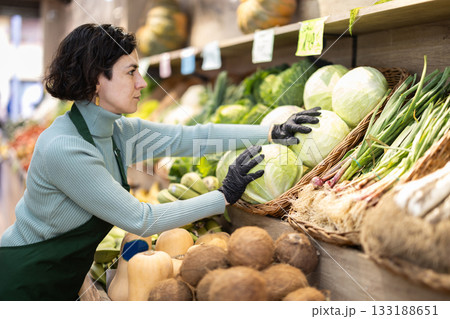Adult woman seller puts cabbage on display Adult woman seller puts cabbage on display 133188651