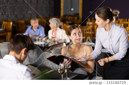 Young couple discussing menu with waitress at table in restaurant Young couple discussing menu with waitress at table in restaurant 133188729