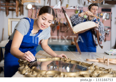 Portrait of skillful repair woman carpenter renovating mirror frame furniture and using brush in woodwork studio Portrait of skillful repair woman carpenter renovating mirror frame furniture and using brush in woodwork studio 133188753