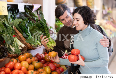 Couple man and woman choosing tomatoes and spinach Couple man and woman choosing tomatoes and spinach 133188755