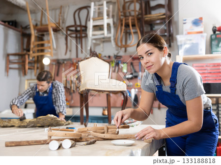 Restorer woman carefully cleans dirt and dust from carved wooden decor element 133188818