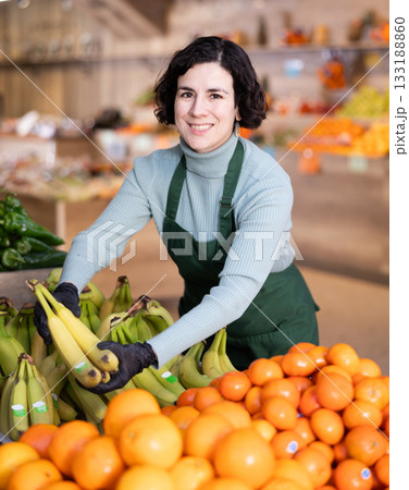 Woman shop seller puts banana goods on display case 133188860