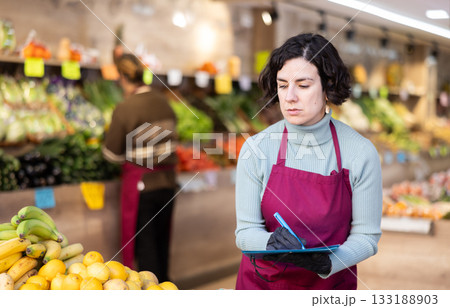 Woman seller take inventory with list in vegetable shop Woman seller take inventory with list in vegetable shop 133188903