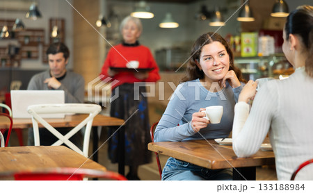 Girl in cafe sits opposite female companion, has nice conversation Girl in cafe sits opposite female companion, has nice conversation 133188984