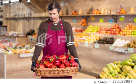 Adult man seller with basket of bell peppers 133188987
