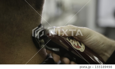 Barber giving a man haircut with electric clipper. Clip 133189498