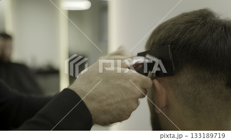 Barber giving fade haircut with electric clipper. Clip Barber giving fade haircut with electric clipper. Clip 133189719