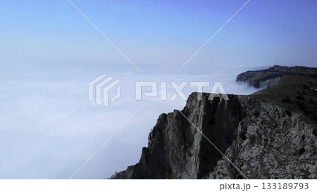 Rocky mountain cliff emerging above flowing clouds. Media 133189793