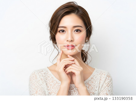 顔周りに後れ毛を出した華やかなまとめ髪と上品な白のレーストップスを着た女性 133190358