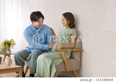 ソファに座ってくつろぐ若い夫婦 妊婦さん ソファに座ってくつろぐ若い夫婦 妊婦さん 133190664