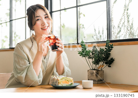 カフェでランチ,モーニング,ブランチにサンドイッチとアイスコーヒーを飲む若いアジア人女性 カフェでランチ,モーニング,ブランチにサンドイッチとアイスコーヒーを飲む若いアジア人女性 133190745