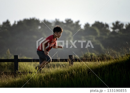 ＜素材＞夕暮れの公園を走る男の子 133190855