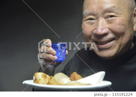 湯気の立ち昇るおでんを食べる笑顔の老人 133191224