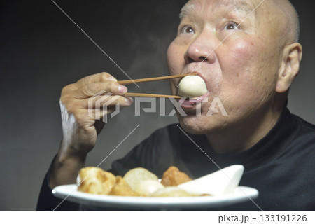 湯気の立ち昇るおでんを食べる笑顔の老人 133191226